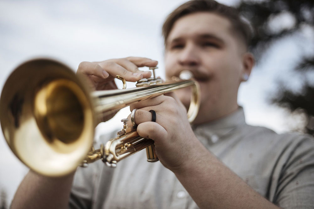 Ein Mann spielt Trompete und provoziert damit eine Beschwerde wegen Lärmbelästigung durch Nachbarn.