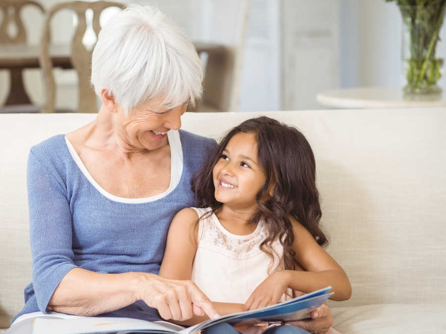 Eine Großmutter liest ihrer Enkelin ein Buch vor. Sie hat Großelternzeit beantragt.