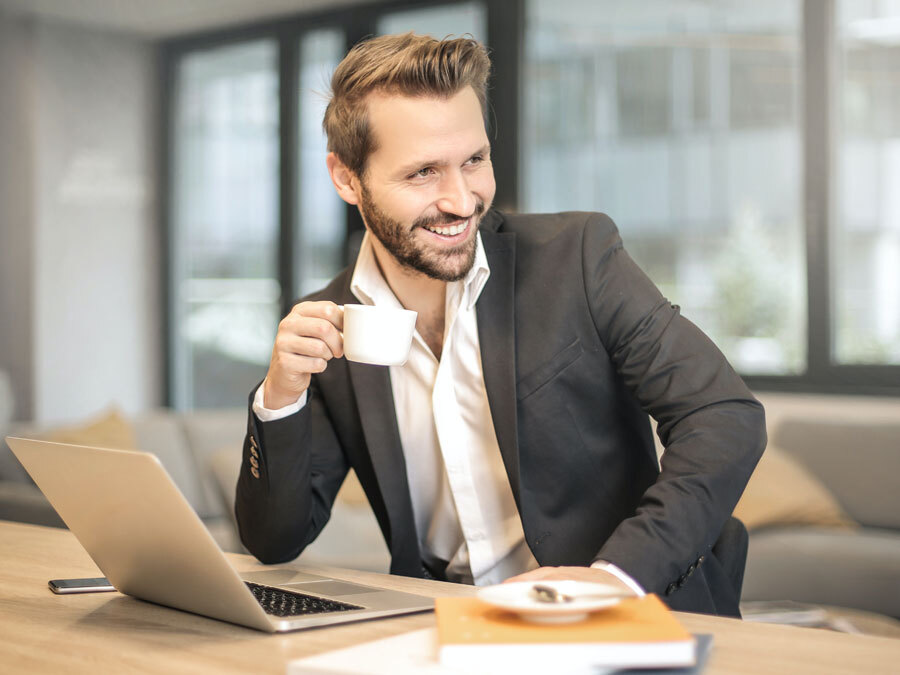 Ein Mann sitzt vor einem Rechner und macht gerade ein Kaffeepause. Er nutzt eine Methode zum Stessabbau.
