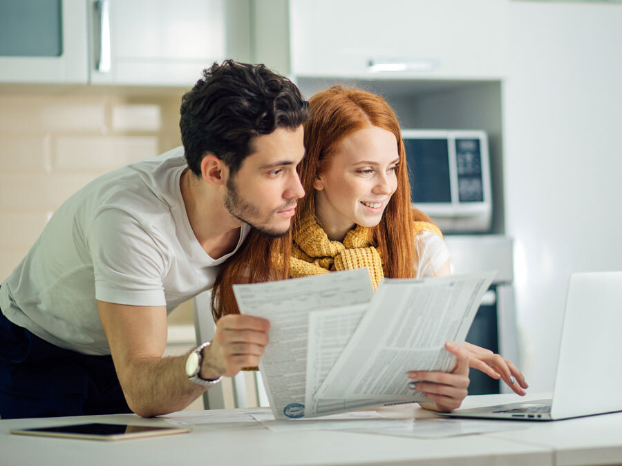 Ein junger Mann und eine junge Frau schauen sich gemeinsam Grundsteuererklärung Formulare an.