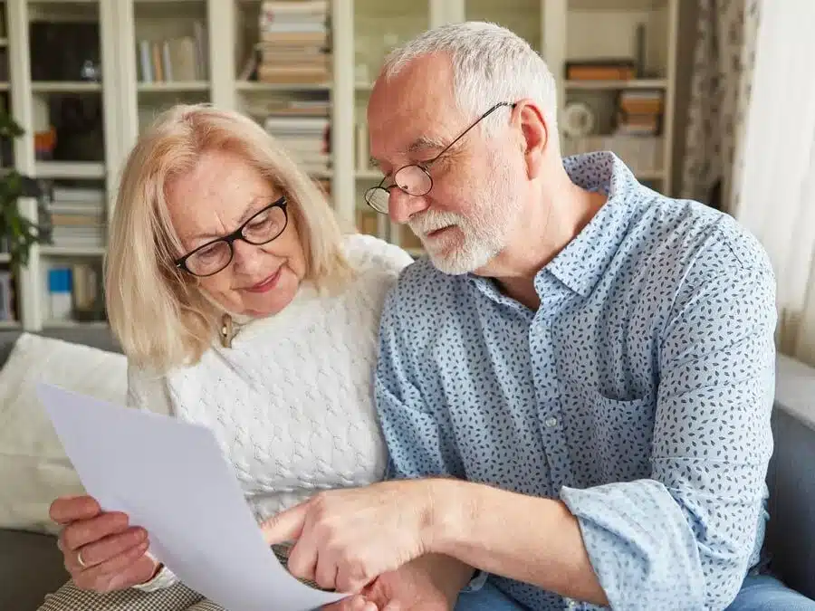 Eine ältere Frau und ein älterer Mann schauen sich ein Dokument an.